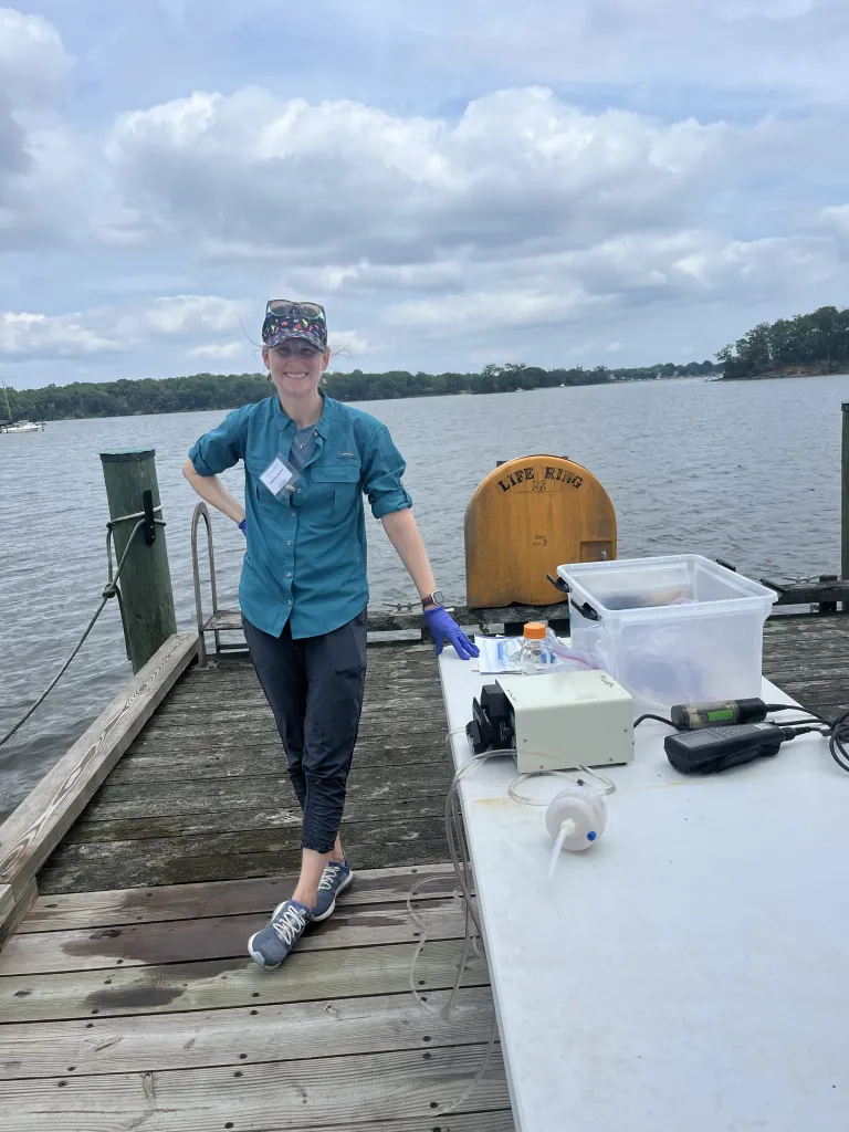 A woman stands on a dock smiling at the camera